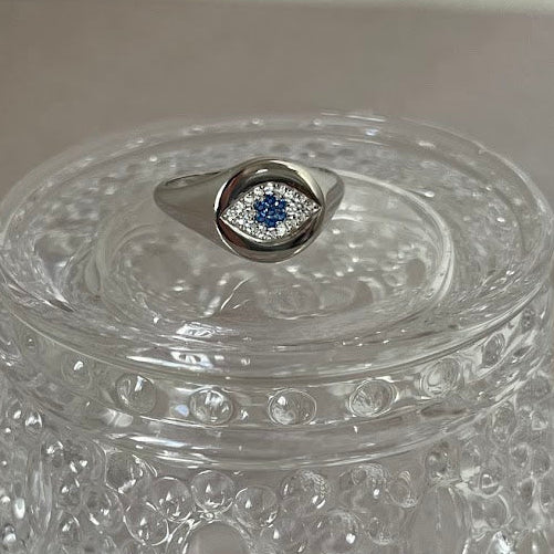 Clear decorative box with a silver ring featuring a blue gemstone on a gray surface.